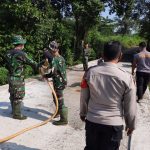 TNI – Polri Bersama Warga Gotong Royong Siram Jalan Yang Sudah Dicor